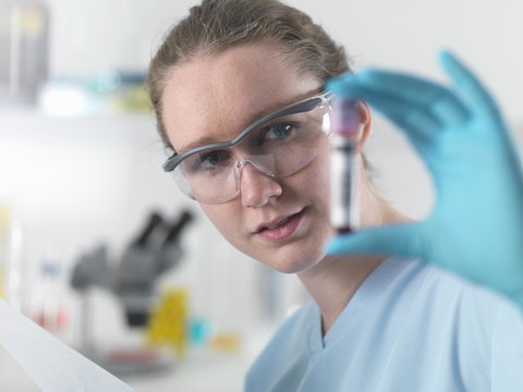 Technician holding bar coded blood sample in clinical laboratory