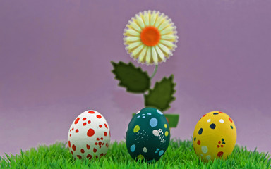 Ostergruss mit gepunkteten bunten Ostereiern und einer Blume