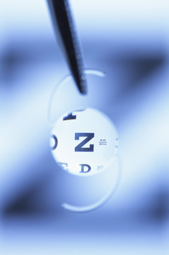 Snellen eye chart seen through an intraocular lens. Intraocular lens is artificial and surgically implanted in the human eye following extraction of the natural crystalline lens clouded by cataract.