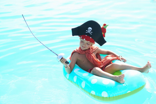 Boy lounging on rubber ring in pool dressed up as a pirate