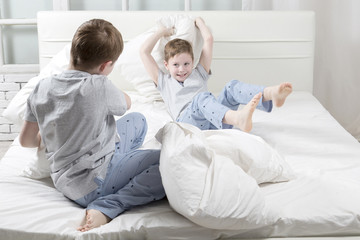 Young children playing on the bed. Pillow fight