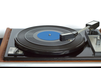 Old vintage turntable in wooden case with rotation vinyl record with blue label isolated on white background. Horizontal photo front view closeup