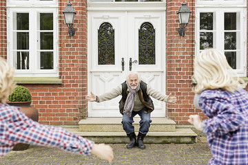 Grandfather welcoming grandchildren with arms open