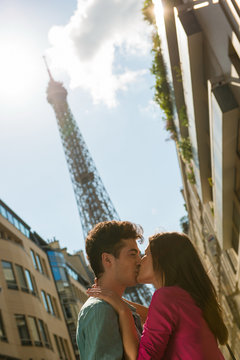 Young couple sharing a kiss in front of  Eiffel Tower, Paris, France