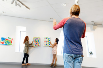 Young artists in gallery hanging painting on walls