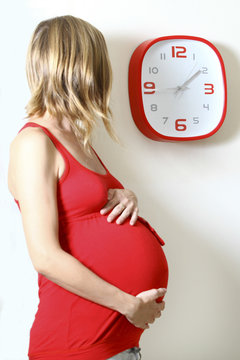 Pregnant woman clock watching in kitchen