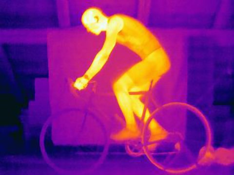 Side view thermal image of young male cyclist in training, showing the heat of the muscles and of the bicycle tires