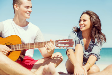 Beautiful young people with guitar on beach
