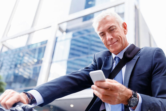 Successful businessman on bicycle with mobile phone
