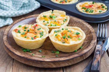 Mini quiche with chicken and bell pepper on a wooden plate