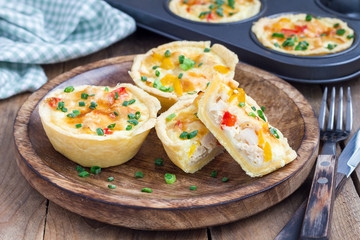 Mini quiche with chicken and bell pepper on a wooden plate