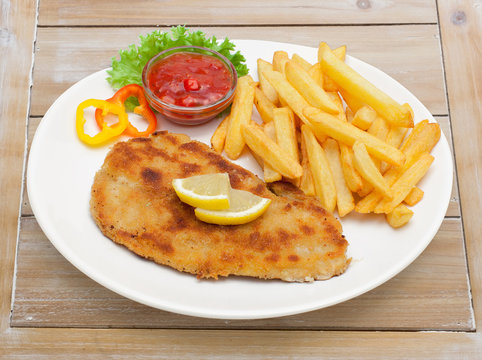 Zigeunerschnitzel mit Pommes auf Holzuntergrund