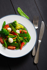 Salad with young peas, broccoli, cherry tomatoes and mozzarella
