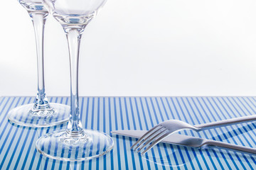 Weingläser und Besteck auf blau gestreifter Glastischplatte