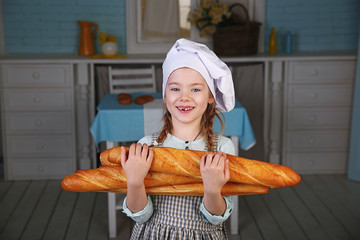 Little girl in scullion's dress holding bread and posing on the kitchen