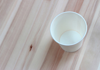 Fototapeta na wymiar White paper cup on a wooden table