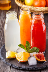 Fresh citrus juices on a dark wooden background.
