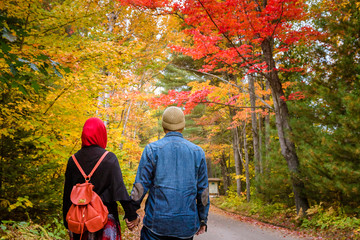 Muslim couple with colourful trees as background during autumn season