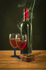A bottle of wine, a glass and lit a cigar