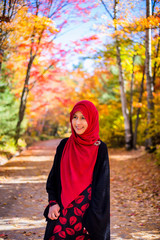 Muslim woman wearing hijab with colourful trees as background during autumn season