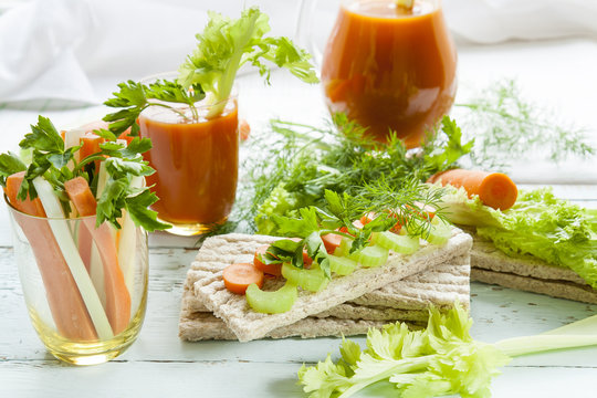 Plain rye cakes, galette rye with fresh carrots, celery and parsley around fresh carrot juice, fresh carrot and celery on light background