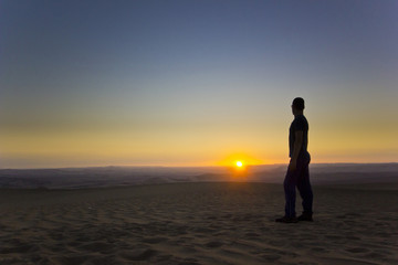 Fototapeta na wymiar standing man at sunset in desert
