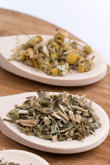 Chamomile nettle and basil tea on a wooden spoon