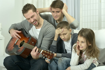 man playing the guitar for his family