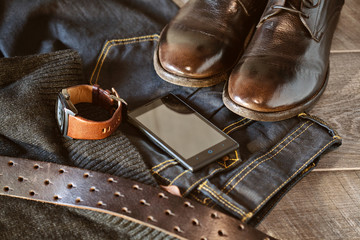 still life clothing and accessories - shoes, jeans and a leather belt, wrist watch, smartphone