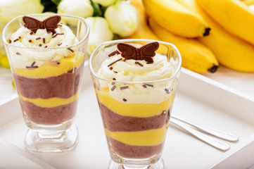 Chocolate and banana pudding on white wooden tray.