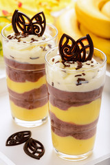 Chocolate and banana pudding on white wooden tray.