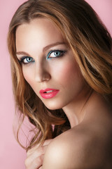 Beauty Model Woman Face on pink shiny background. Perfect Skin. Professional Make-up.Blue eyes and pink lips. Natural beauty