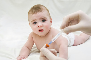 Baby is starring on syringe with immunization vaccine