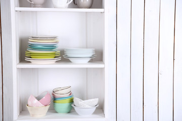 Different clean dishes on wooden shelves