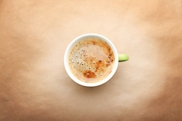 Cup of coffee on beige background, top view