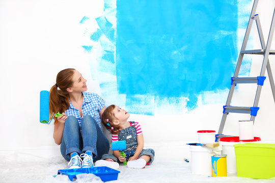 happy family mother and child daughter making repairs, paint wal