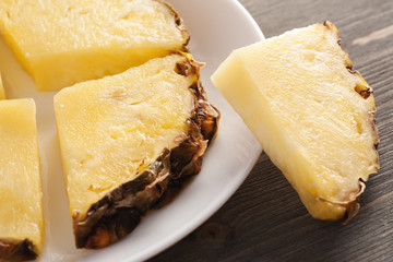 Sliced pineapple pieces on white ceramic plate