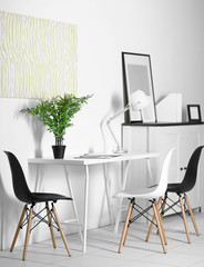 Room interior with commode, frames, chairs and table on white wall background