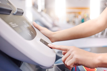 Fototapeta premium woman adjusts the treadmill at the beginning of training, do fitness in the sport club