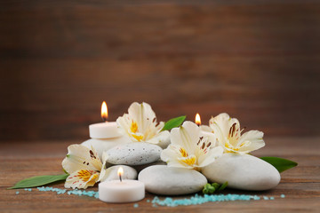 Fototapeta na wymiar Spa still life with stones, flowers and candlelight on wooden background
