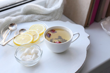 Tea set on a white wooden tray on the windowsill
