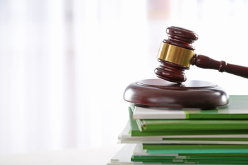 Gavel with stack of notebooks on light blurred background