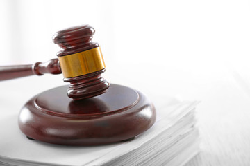 Gavel on stack of paper on light blurred background