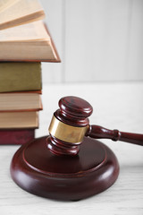 Gavel with books on wooden table closeup