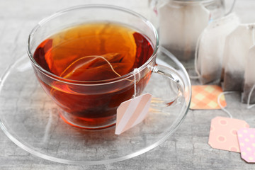 Cup of tea with tea bags on grey background