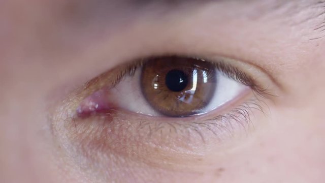 Big close up of a man's brown eye looking at the camera and looking around.  Recorded in 4K.