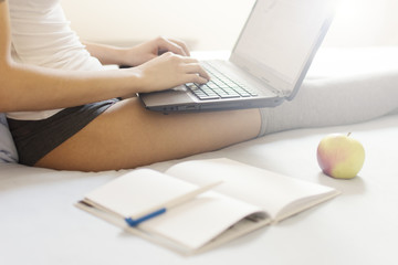 Fototapeta premium Top view of girl typing on laptop in bed