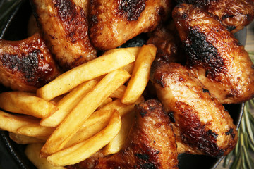Baked chicken wings with French fries, close up