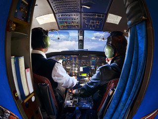 The cabin of the old passenger plane with pilots, mountains and sky outside the window