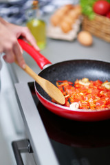 Human hands with frying pan on stove, closeup